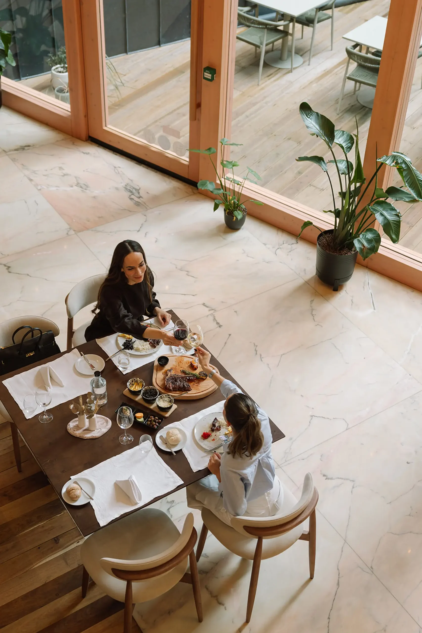 Duas pessoas jantando em restaurante elegante com pratos e vinho.
