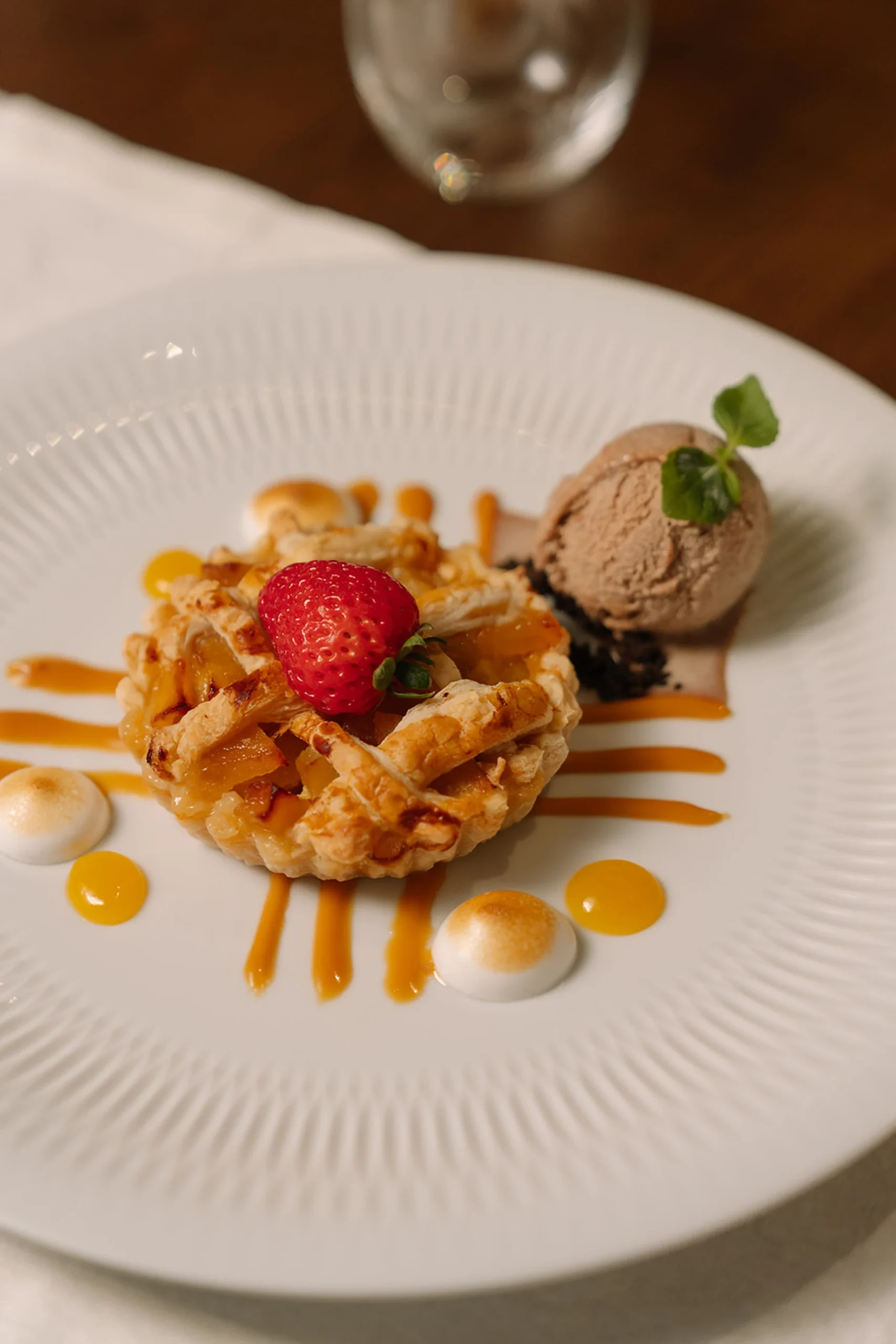 Sobremesa com torta de frutas, sorvete e calda decorativa.