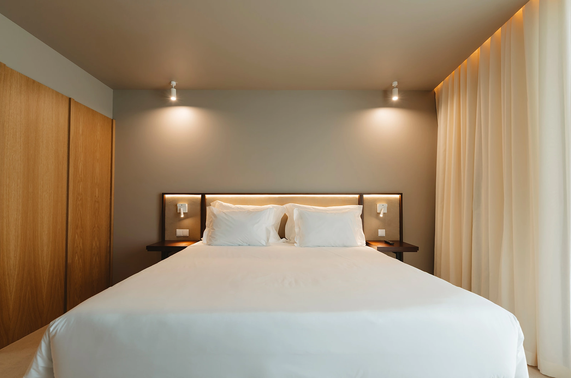 Quarto moderno com cama de casal e ilumina&ccedil;&atilde;o suave.