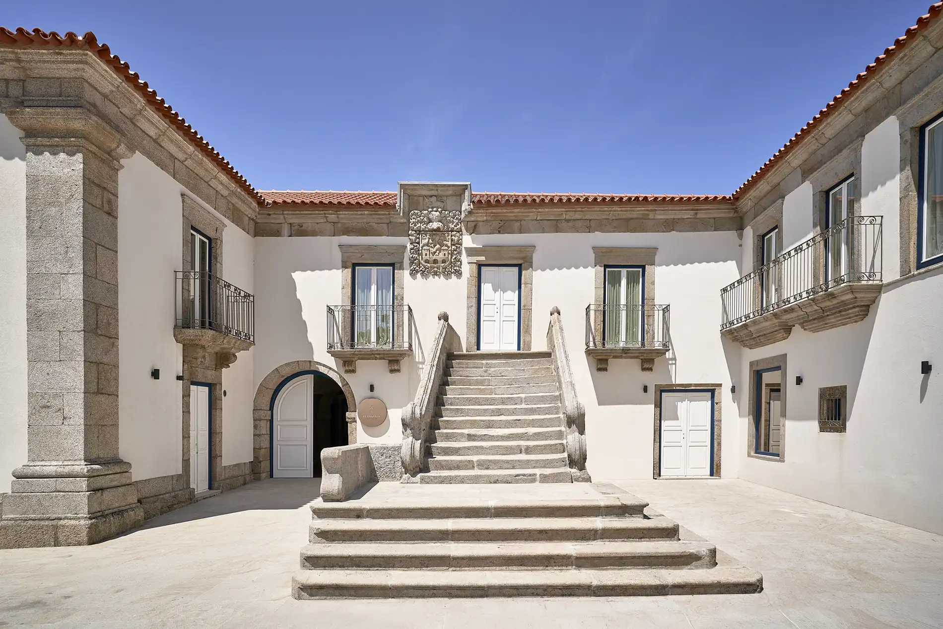 Fachada de edif&iacute;cio hist&oacute;rico com escadaria central e c&eacute;u azul.