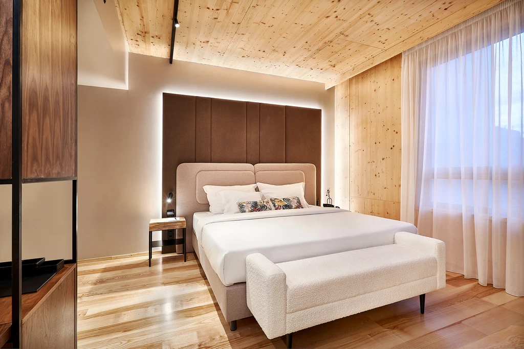 Quarto moderno com cama de casal e ilumina&ccedil;&atilde;o suave.
