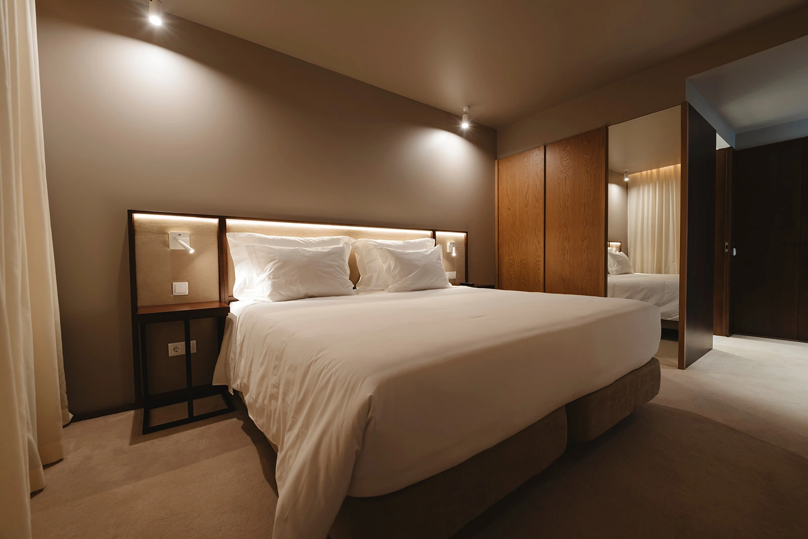 Quarto moderno com cama king, ilumina&ccedil;&atilde;o embutida e arm&aacute;rios de madeira