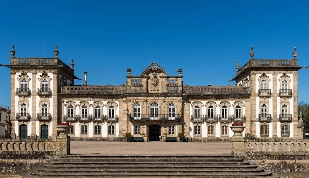 Pal&aacute;cio barroco com fachada ornamentada sob c&eacute;u azul.