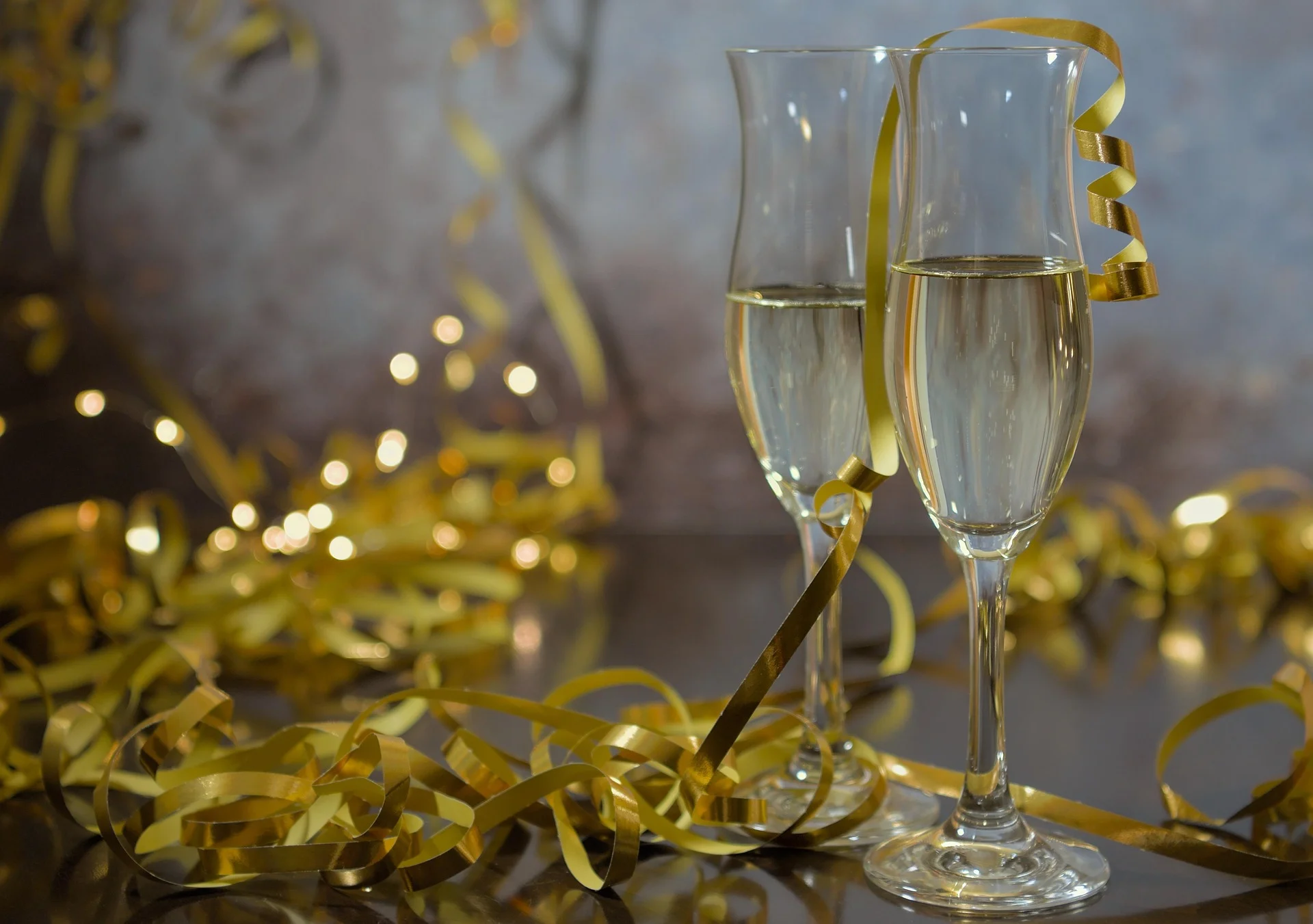 Ta&ccedil;as de champanhe com fitas douradas em clima de celebra&ccedil;&atilde;o