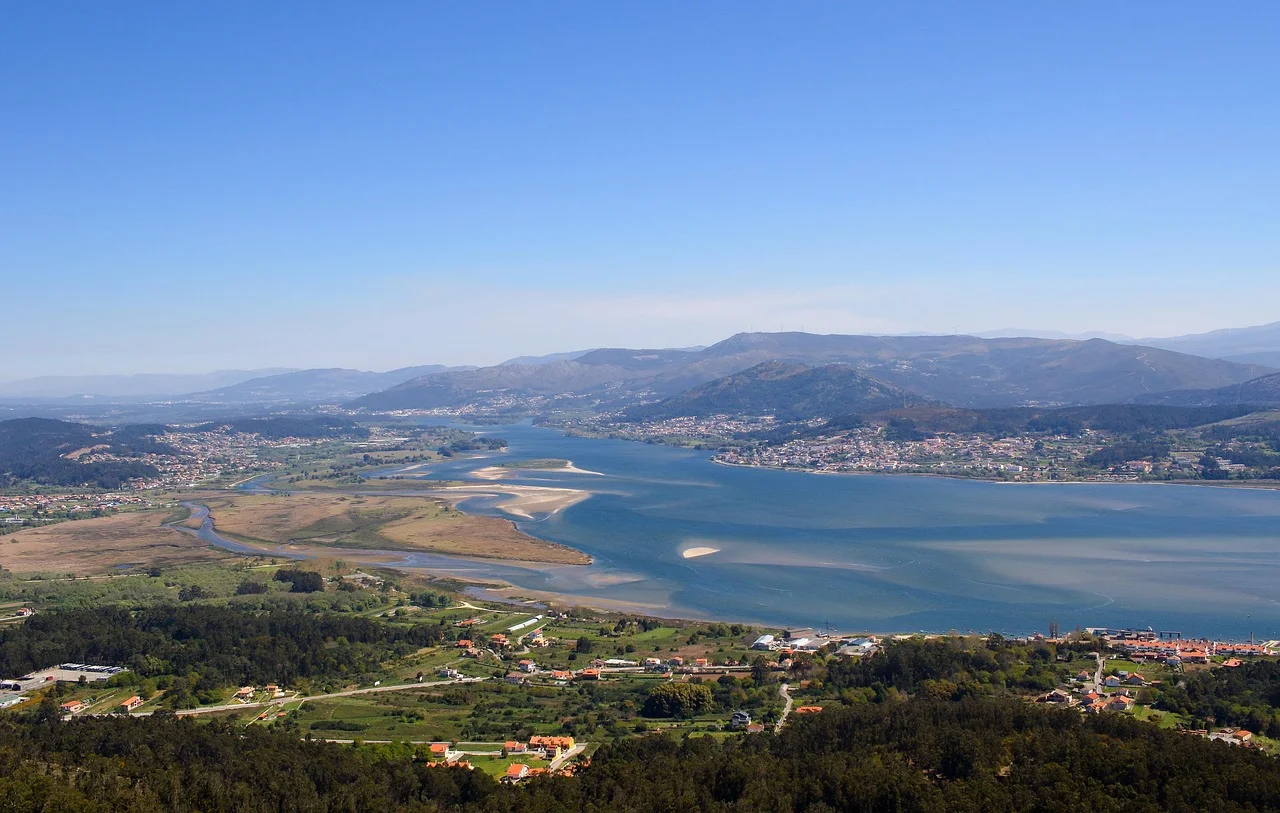 Vista a&eacute;rea de um rio serpenteando por uma paisagem com montanhas ao fundo.