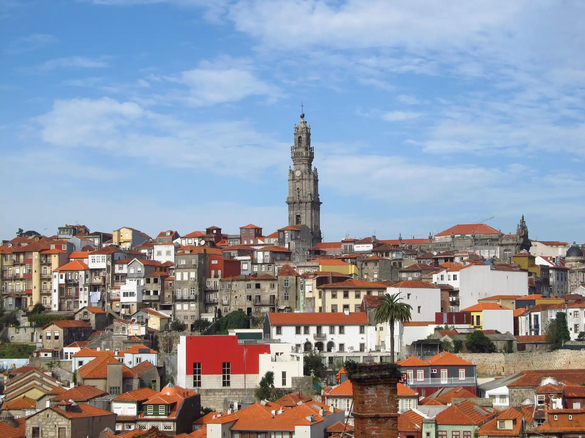 Cidade hist&oacute;rica com torres e telhados vermelhos sob c&eacute;u azul.
