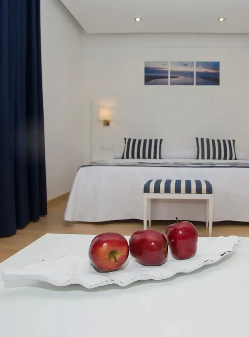 Manzanas rojas sobre una mesa blanca, en un dormitorio moderno con cama y cortinas