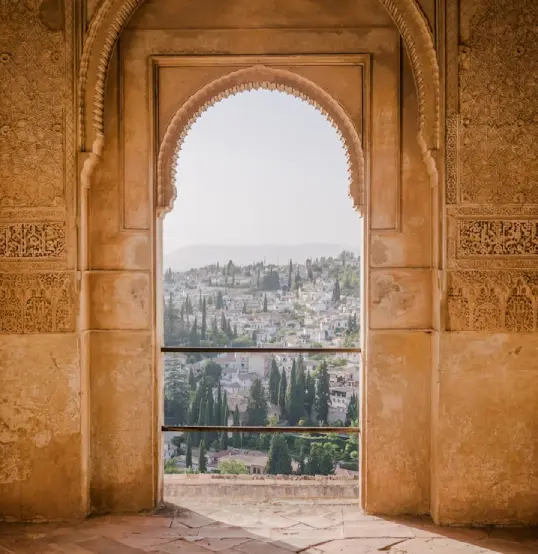 Ventana de piedra con vista panor&aacute;mica de una ciudad y &aacute;rboles.