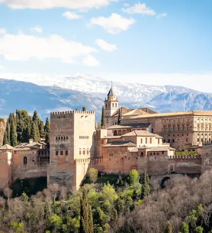 Vista panor&aacute;mica de un castillo en la ciudad con monta&ntilde;as nevadas al fondo