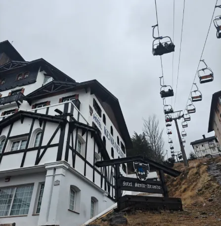 Telef&eacute;rico con cabinas sobre casas de estilo suizo en paisaje monta&ntilde;oso.
