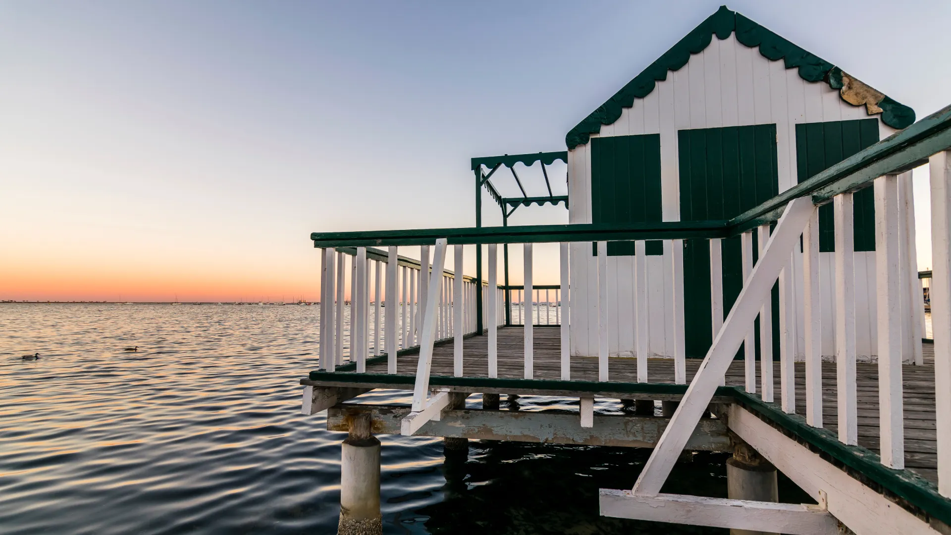 Casa sobre el agua al atardecer con cielo despejado.