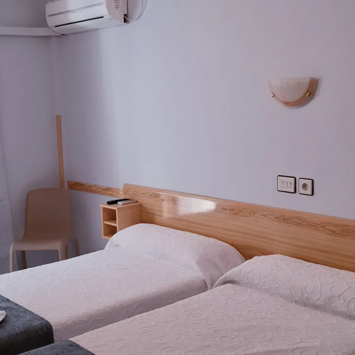 Habitaci&oacute;n con dos camas individuales, aire acondicionado y decoraci&oacute;n sencilla.
