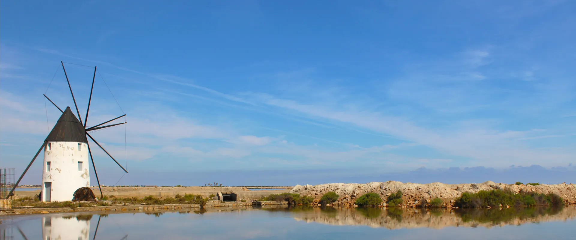 Molino junto a un estanque bajo un cielo azul despejado.