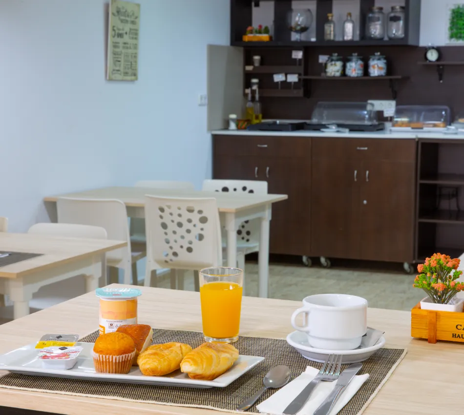 Desayuno con jugo, caf&eacute; y pan en una mesa en una cafeter&iacute;a.
