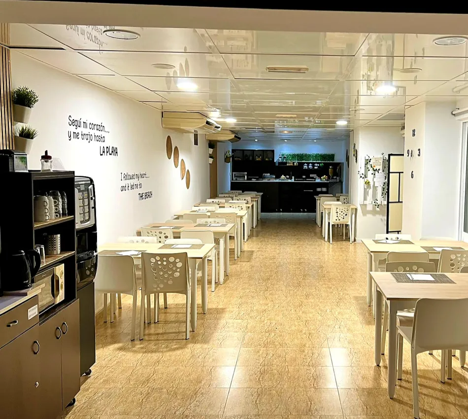 Comedor moderno con mesas blancas y decoraci&oacute;n minimalista en las paredes.