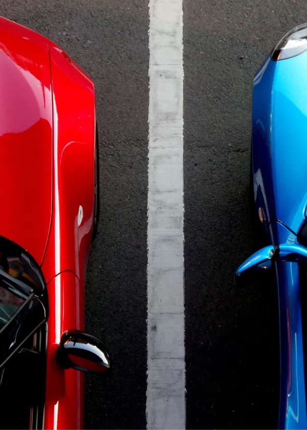 Dos autos, uno rojo y otro azul, estacionados lado a lado.