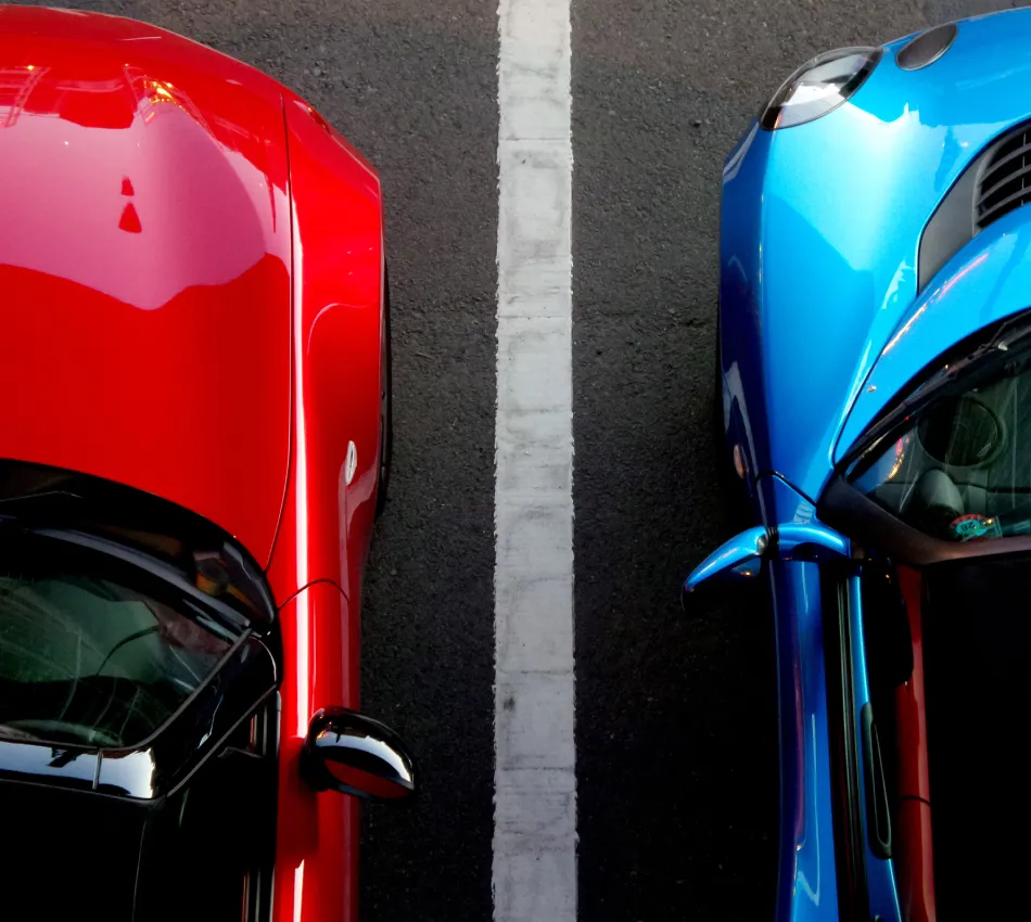 Dos autos, uno rojo y otro azul, estacionados en un espacio delimitado.