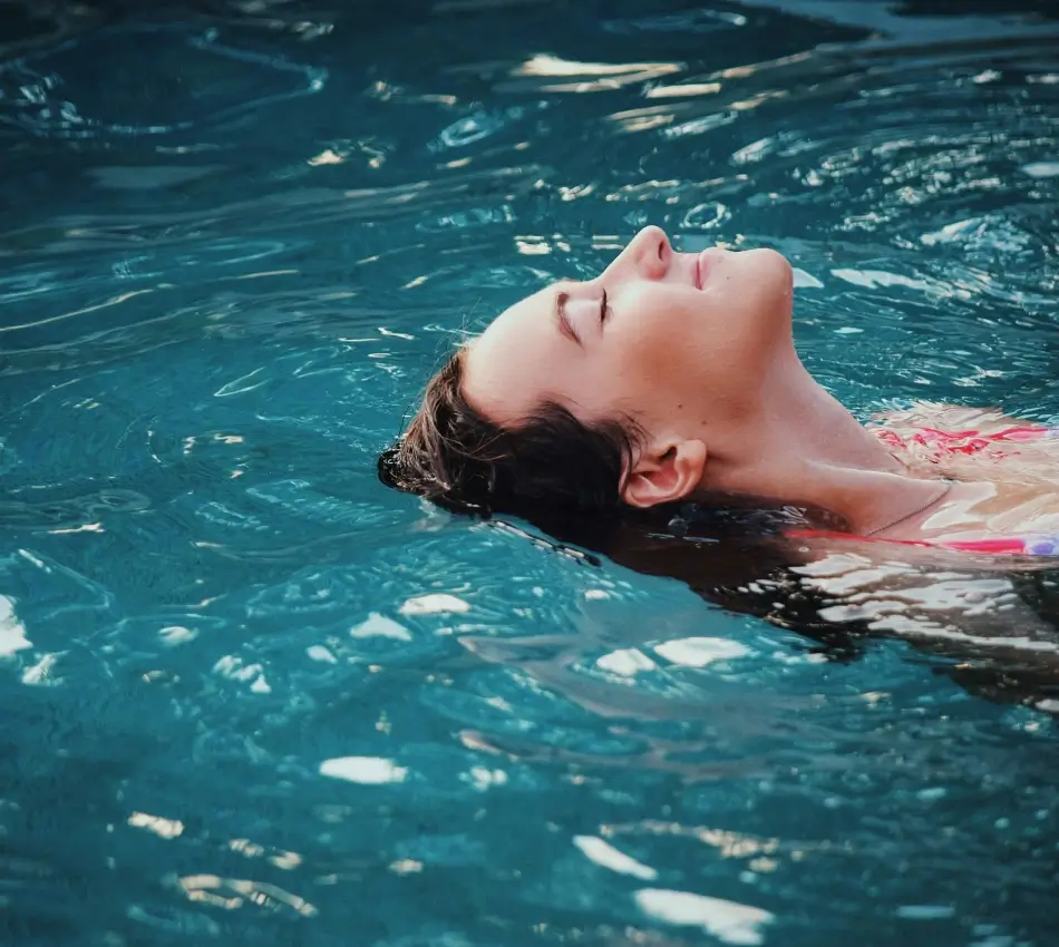 Personne d&eacute;tendue flottant sur l'eau dans une piscine.