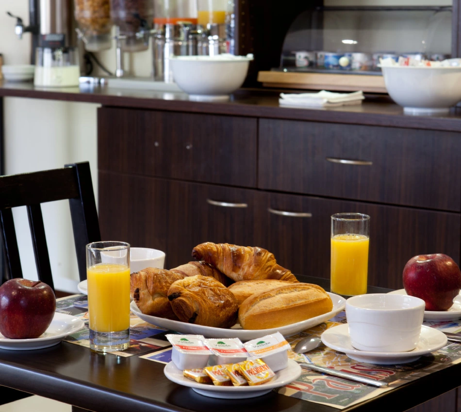 Petit-d&eacute;jeuner compos&eacute; de croissants, pommes, jus d'orange et caf&eacute;.
