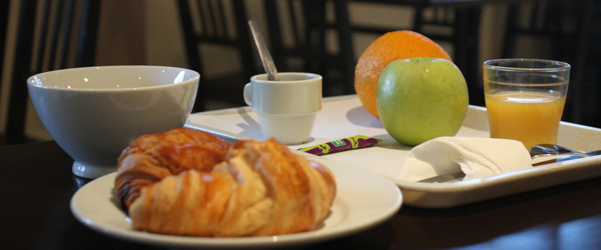 Petit-d&eacute;jeuner avec croissants, jus d'orange, pommes et confitures.