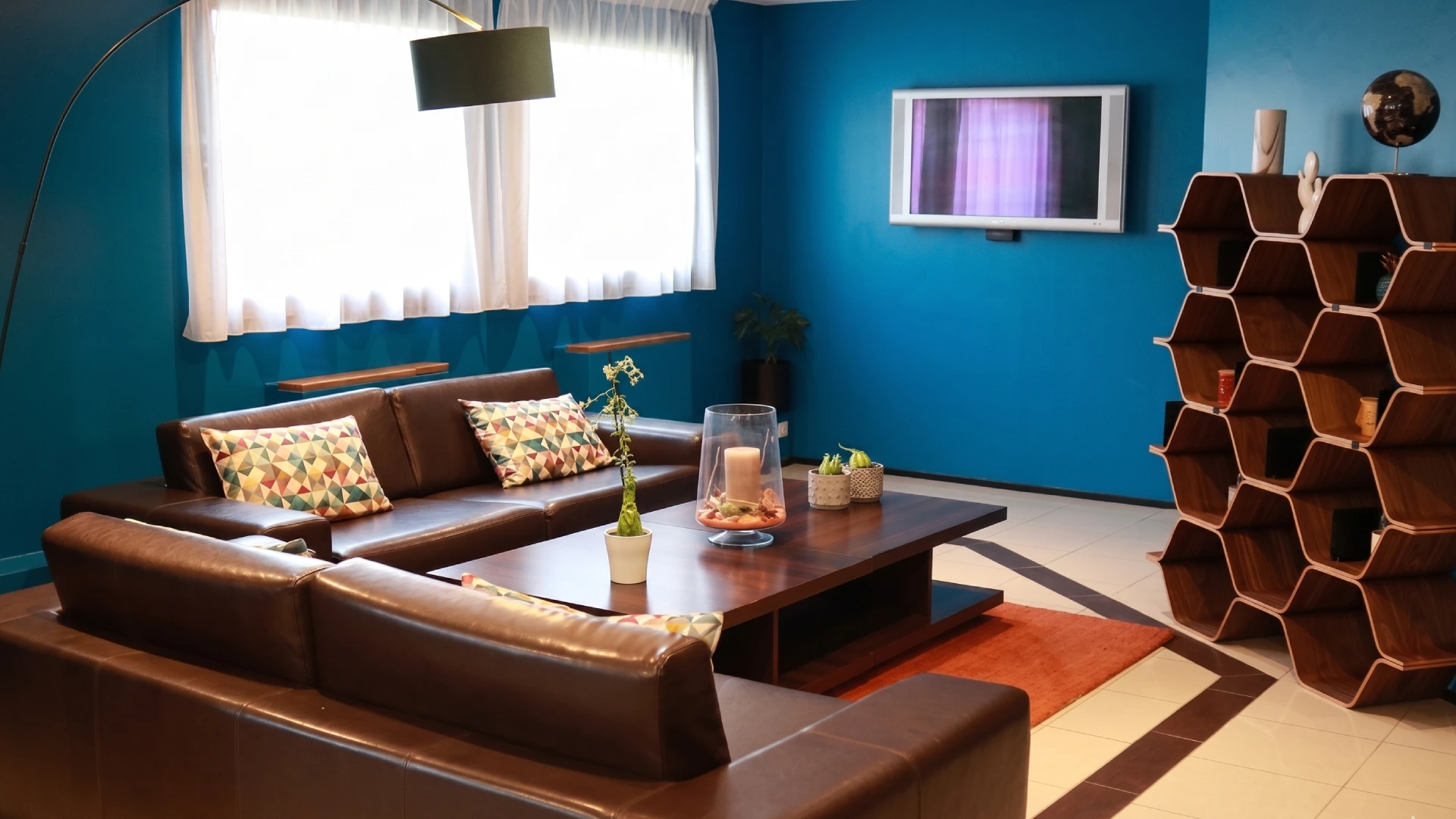 Salon moderne avec murs bleus et canap&eacute; en cuir marron.