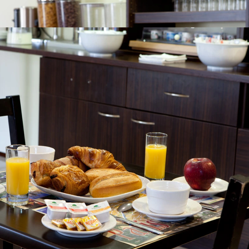 Petit-d&eacute;jeuner sur table : croissants, jus d'orange, pain, pomme, caf&eacute;.