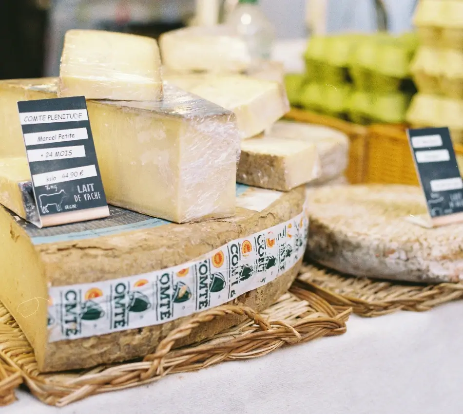 Fromages Comt&eacute; et d'autres assortiments sur une table de pr&eacute;sentation.