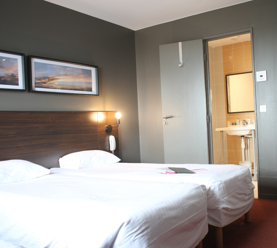 Chambre d'h&ocirc;tel avec deux lits, d&eacute;cor moderne et tableau.