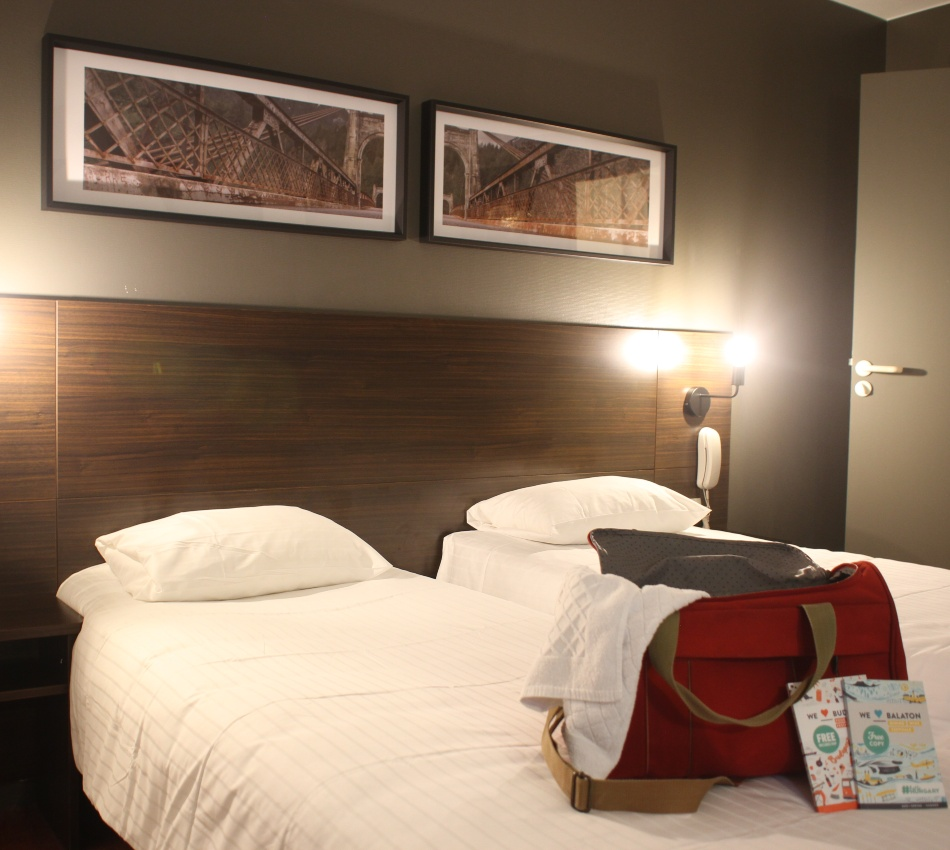 Chambre d'h&ocirc;tel avec deux lits, d&eacute;cor moderne et tableau.
