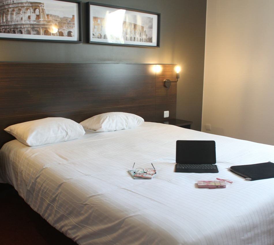 Chambre d'h&ocirc;tel avec un lit, d&eacute;cor moderne et tableau.