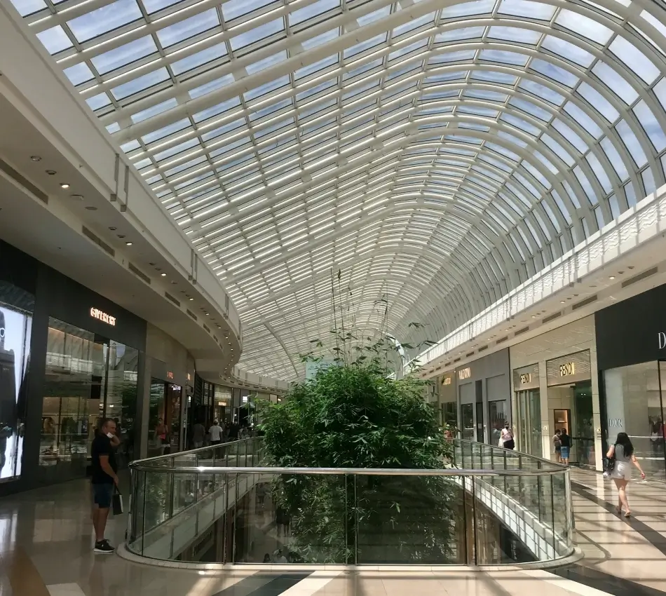 Centre commercial avec plafond en verre et boutiques de luxe.