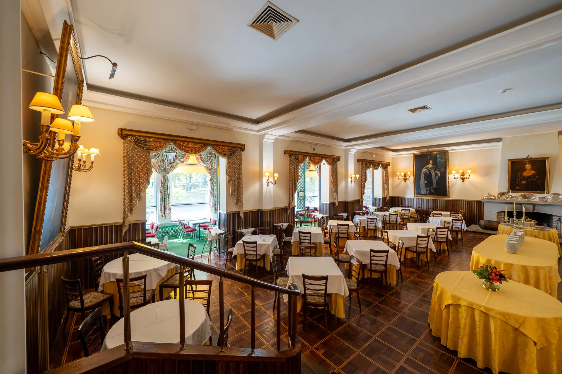 Sal&atilde;o de restaurante com mesas, cortinas e lustres, interior cl&aacute;ssico e iluminado