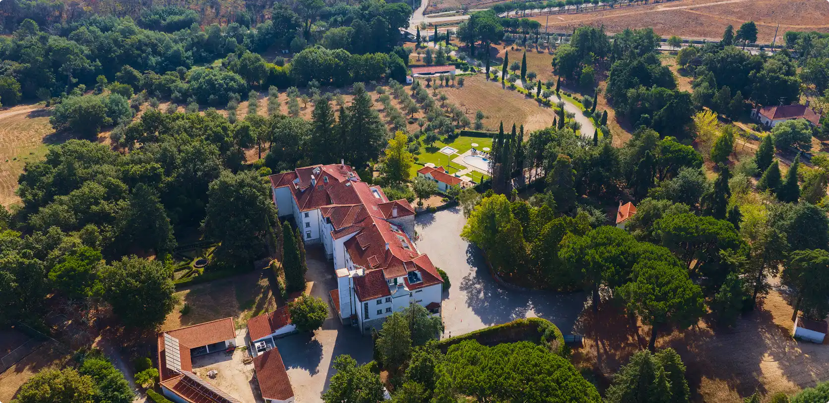 Vista a&eacute;rea de uma fazenda com jardim, piscina e caminhos arborizados