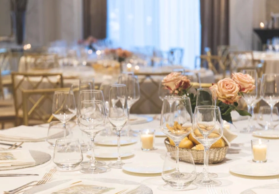 Mesa posta de casamento com arranjo de rosas e velas, ao centro.