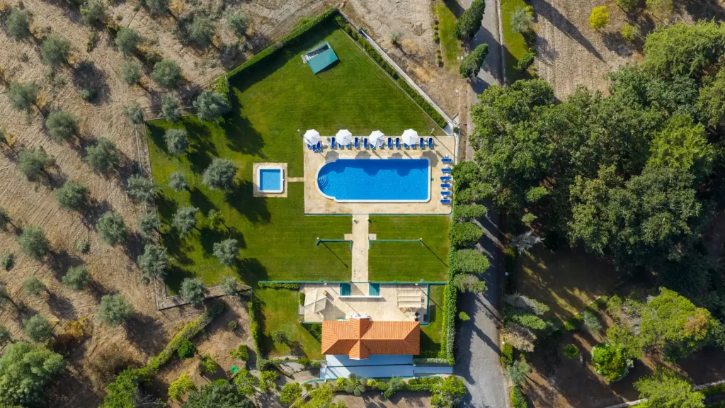 Vista a&eacute;rea de piscina e jardim em propriedade rural com &aacute;rea verde ao redor