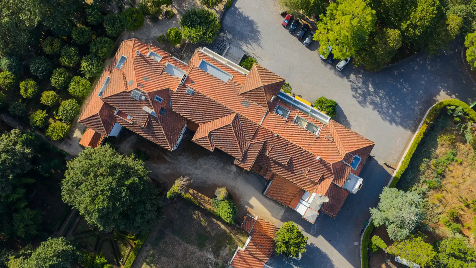 Vista a&eacute;rea de mans&atilde;o com telhado laranja, jardins e caminho com carros estacionados