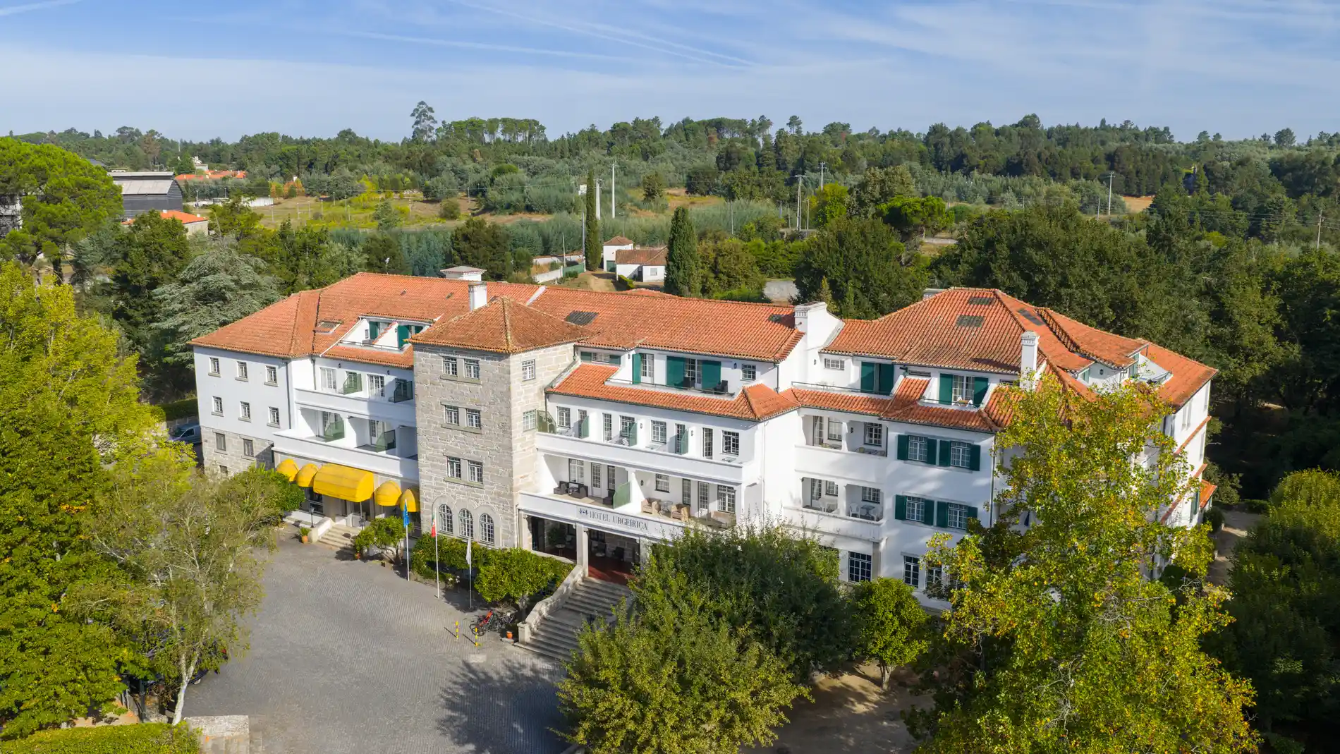 Vista a&eacute;rea de hotel com telhados de cer&acirc;mica e jardim arborizado ao fundo
