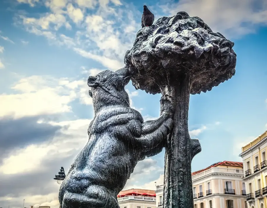 Estatua de bronce de un hombre y un le&oacute;n con cielo nublado de fondo.
