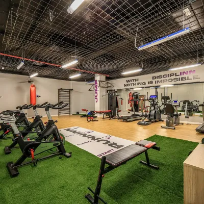 Gimnasio con m&aacute;quinas, pesas y zona de entrenamiento con c&eacute;sped verde