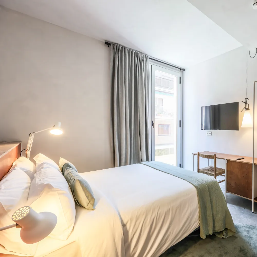 Dormitorio moderno con cama, cortinas grises y puerta hacia el exterior