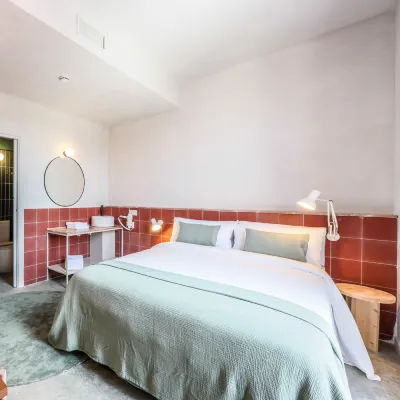 Dormitorio moderno con cama doble, cabecero rojo y l&aacute;mparas de noche.