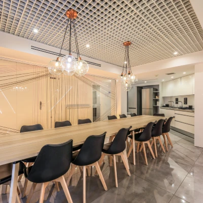 Sala moderna con mesa larga, sillas negras y l&aacute;mparas colgantes.