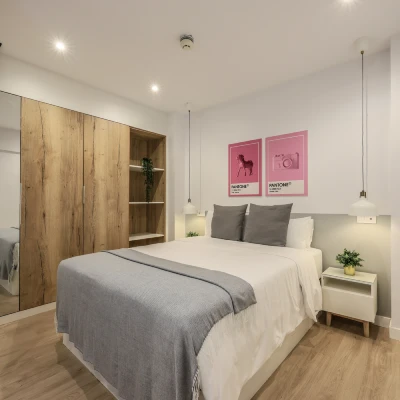 Dormitorio moderno con cama, mesita y panel de madera en pared.
