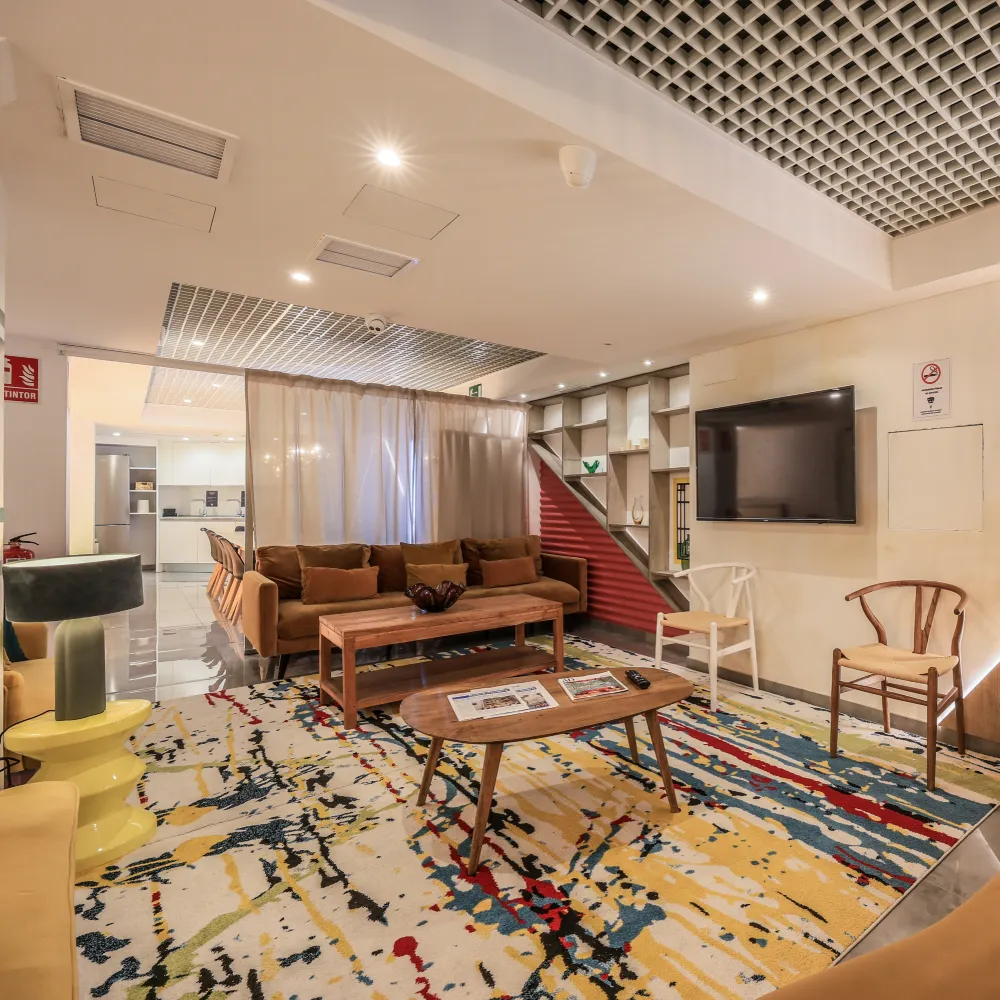 Sala de estar moderna con sof&aacute;s, mesa de madera y alfombra multicolor.