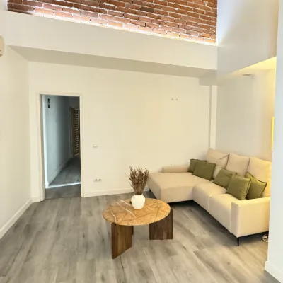 Sala de estar moderna con sof&aacute;, mesa de madera y pared de ladrillo.