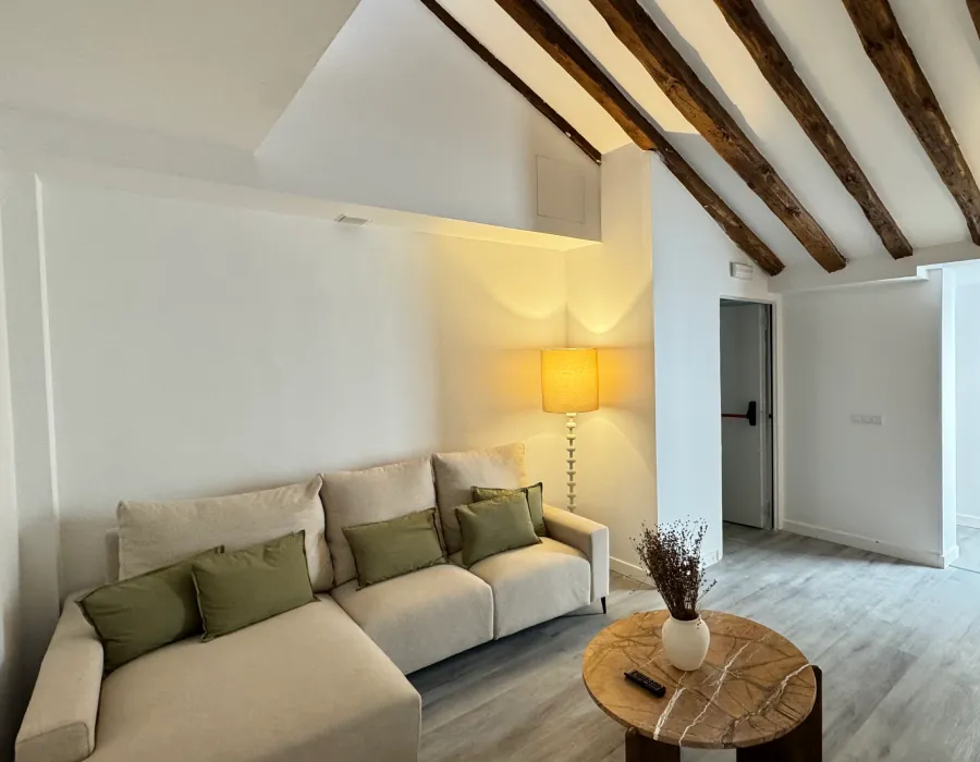Sala moderna con sof&aacute; gris, mesa redonda y vigas de madera en el techo