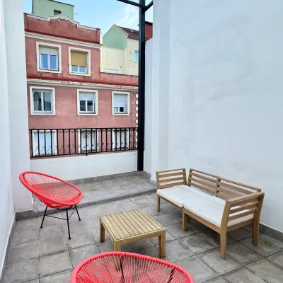 Patio con mesas y sillas de madera y dos sillones rojos con malla.