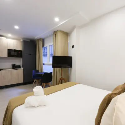 Habitaci&oacute;n de hotel moderna con cama doble y televisi&oacute;n en pared.