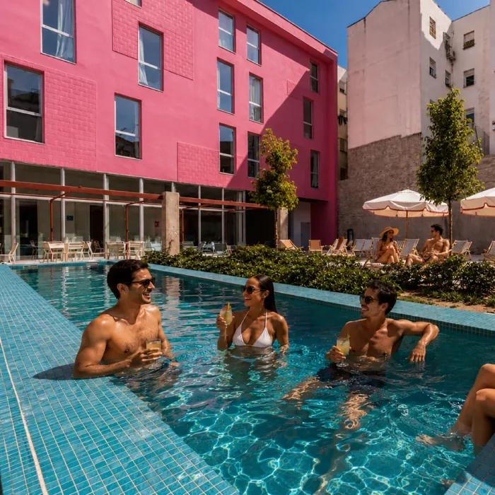 Personas nadando y bebiendo en una piscina junto a edificios de colores.