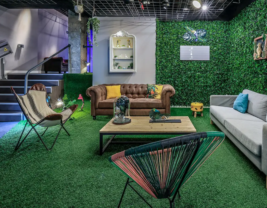 Sala decorada con sillones, mesa de madera y paredes con c&eacute;sped artificial verde